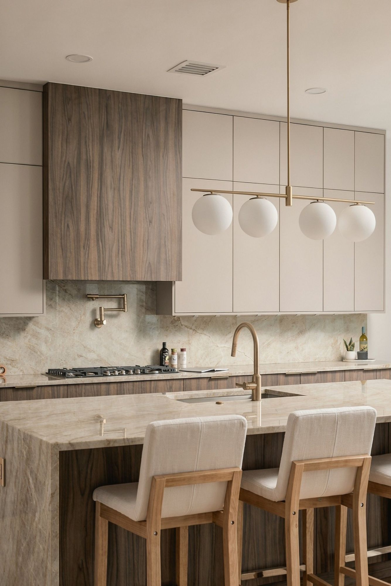 Kitchen island with brass pendant lights and counter stools